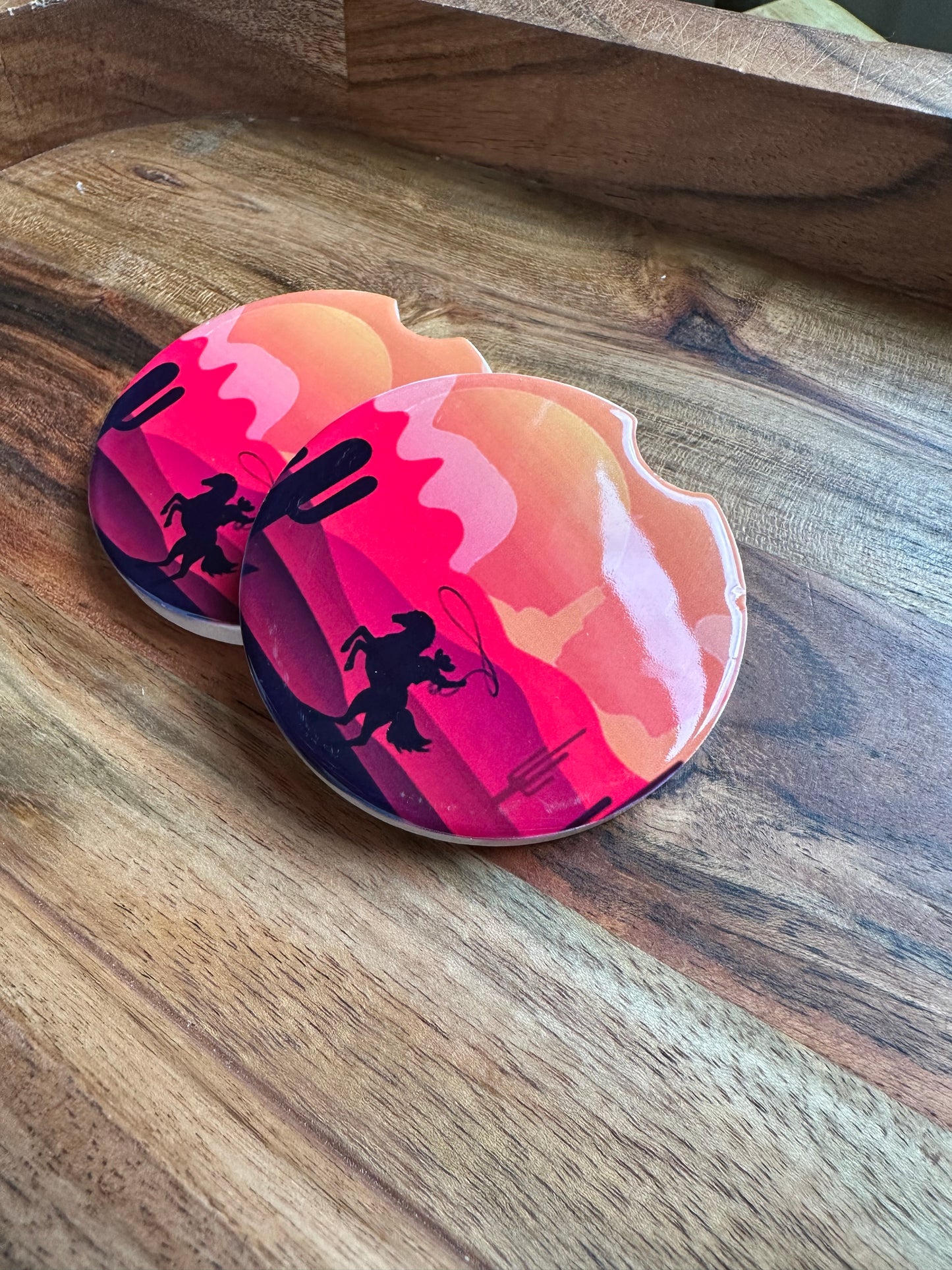 cowboy in a desert sunset ceramic car coaster stacked with a wooden background