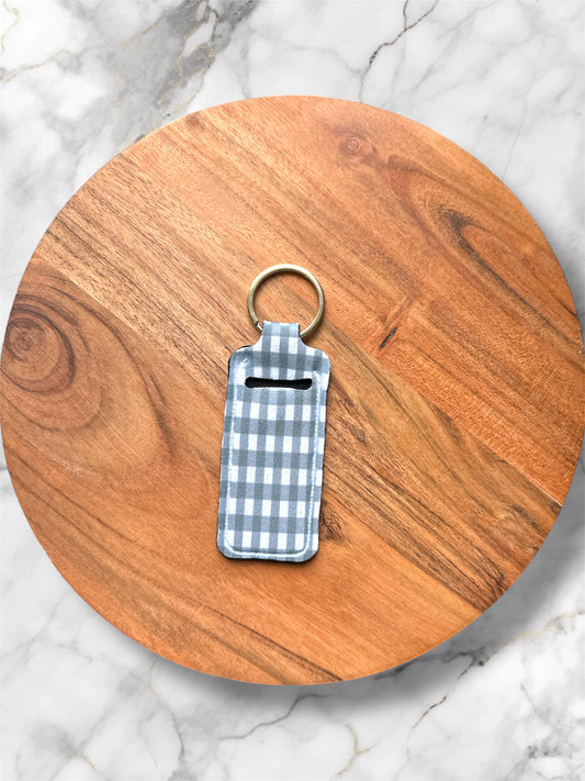 chapstick holder keychain with green and white gingham print design on a wooden board