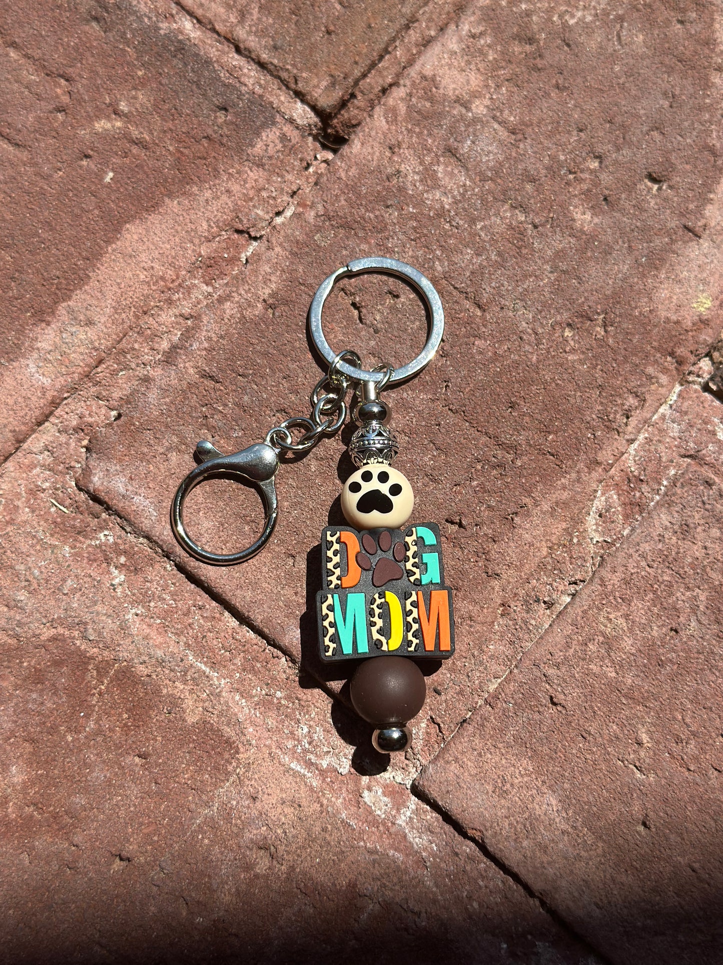 A silicone beaded keychain with a silver post and dog mom cheetah print design, featuring a small clip and keyring.