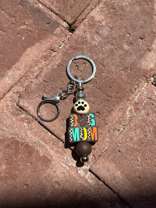 A silicone beaded keychain with a silver post and dog mom cheetah print design, featuring a small clip and keyring.