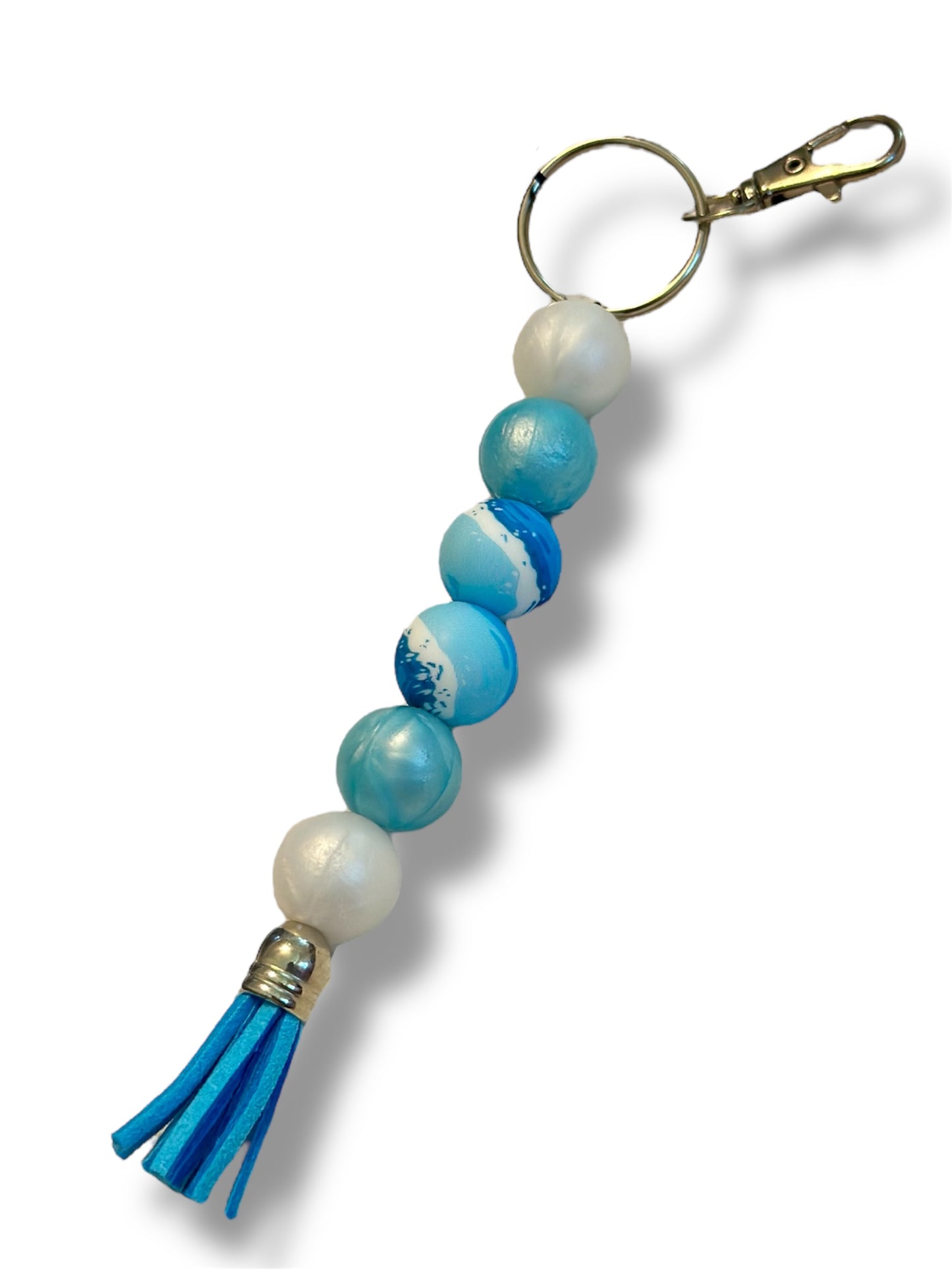A silicone beaded keychain with a wave pattern, featuring pearl and light iridescent blue colors, with a blue tassel at the end.