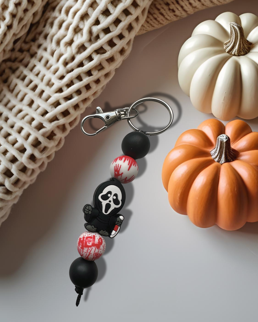 midnight caller silicone beaded standalone keychain on neutral background with knitted fabric and pumpkin