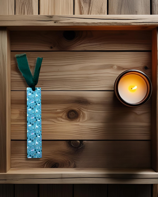 Wooden surface with a lit candle and a blue hardboard bookmark named 'springtime wadle'