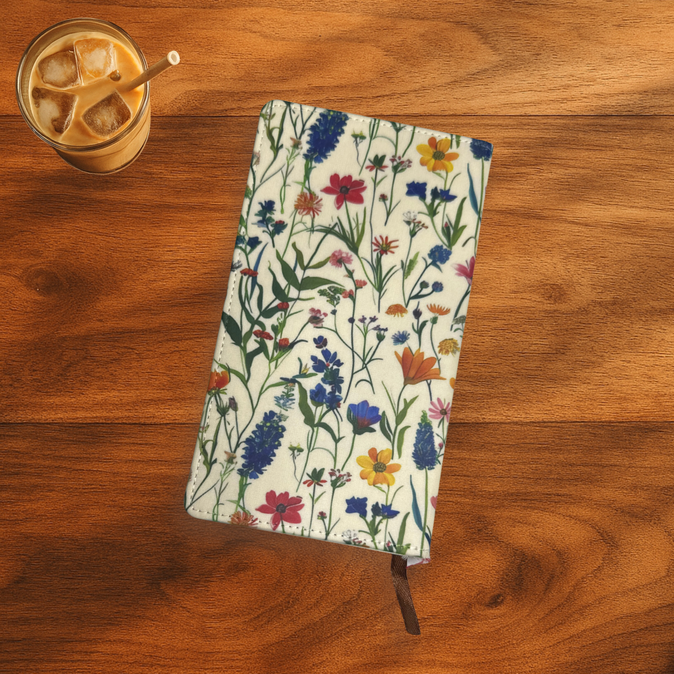 floral print with lavender notebook, the notebook is on a wooden surface next to a glass of iced coffee.