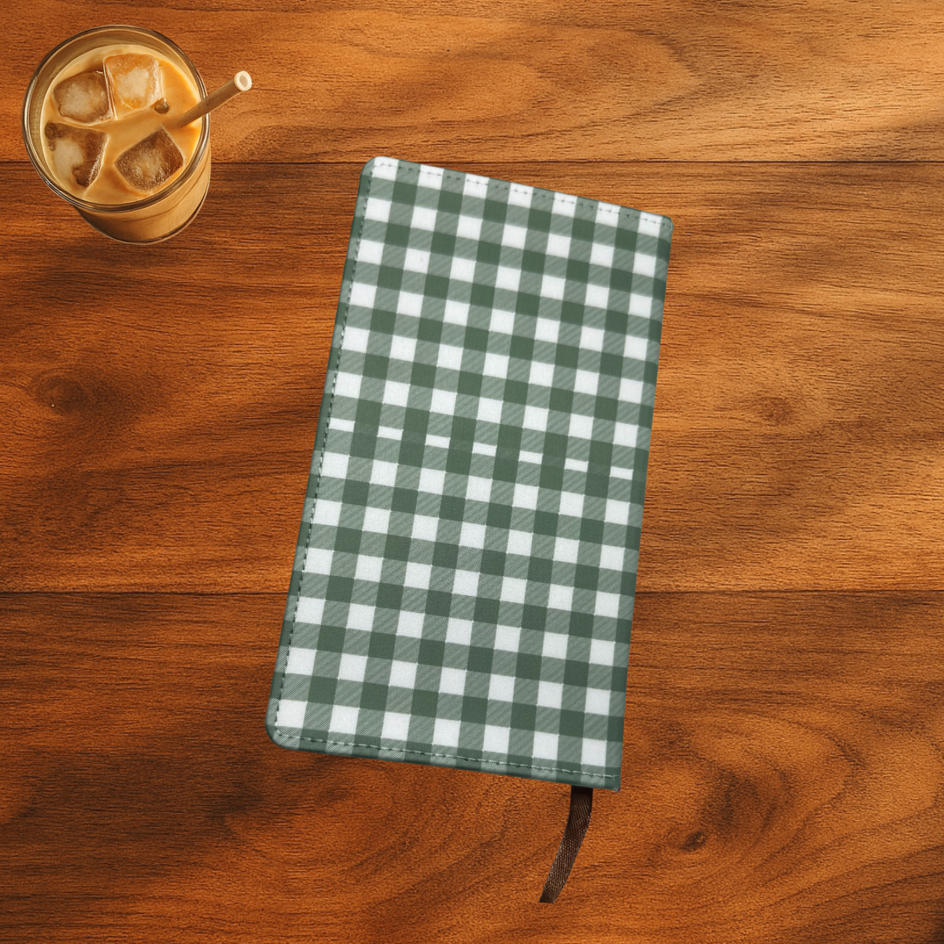 green and white gingham print notebook with Isiah 43:2 verse on the front, the notebook is on a wooden surface next to a glass of iced coffee.