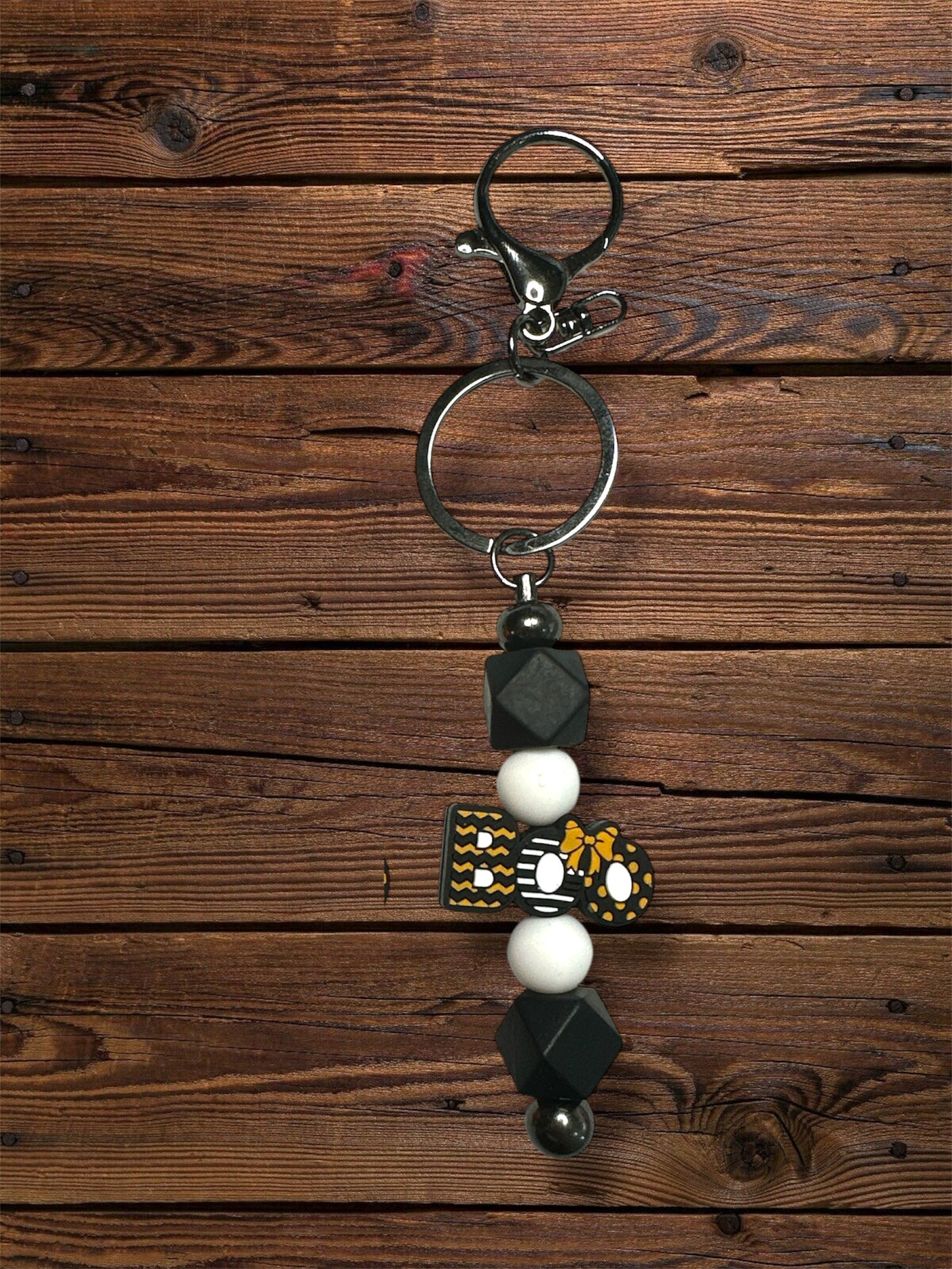 black 'boo' silicone focal beads with white and black beads and silver keychain hardware on a wooden table