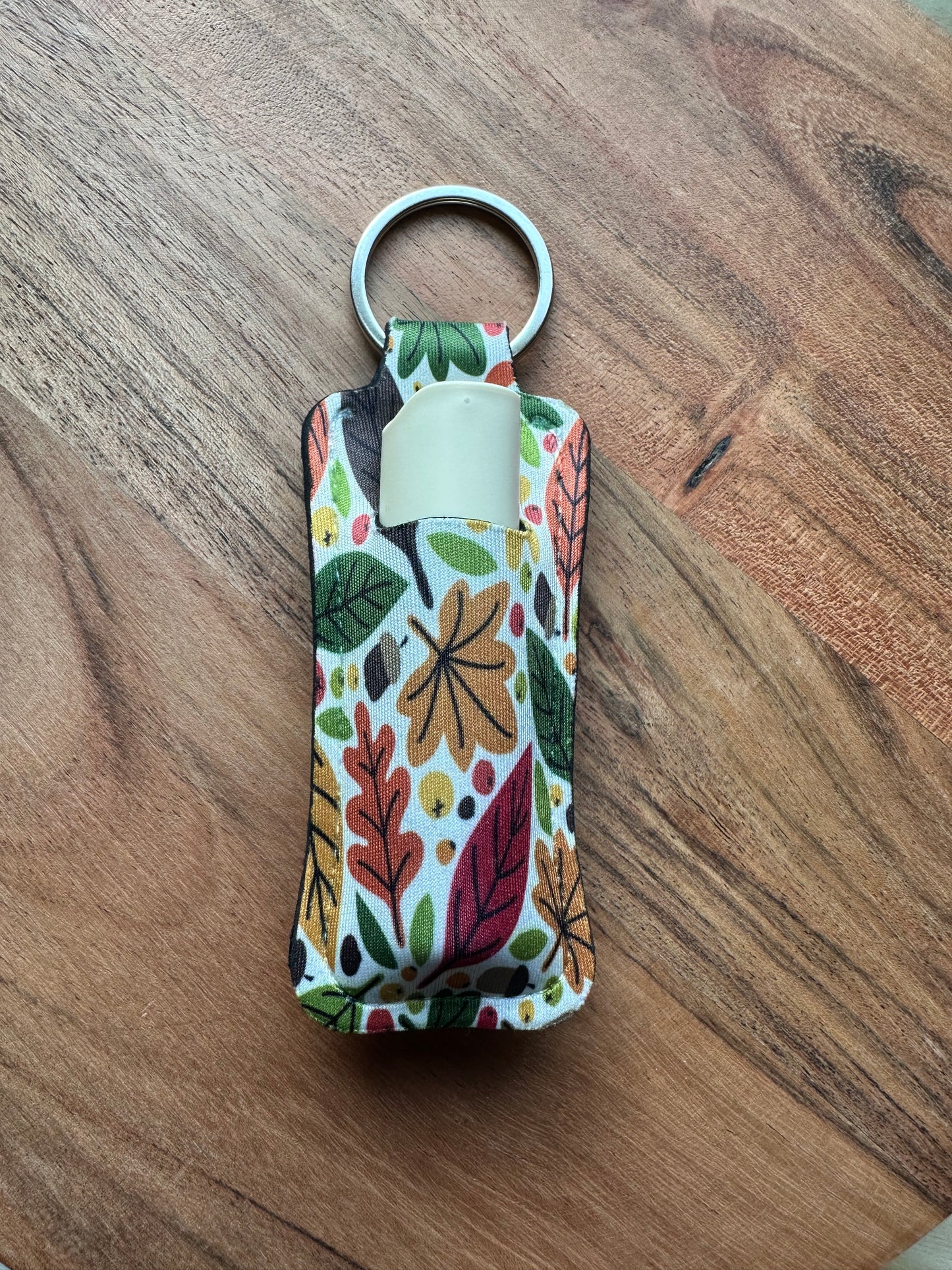 cream Autumn/ Fall themed lip balm holder keychian on a wooden background