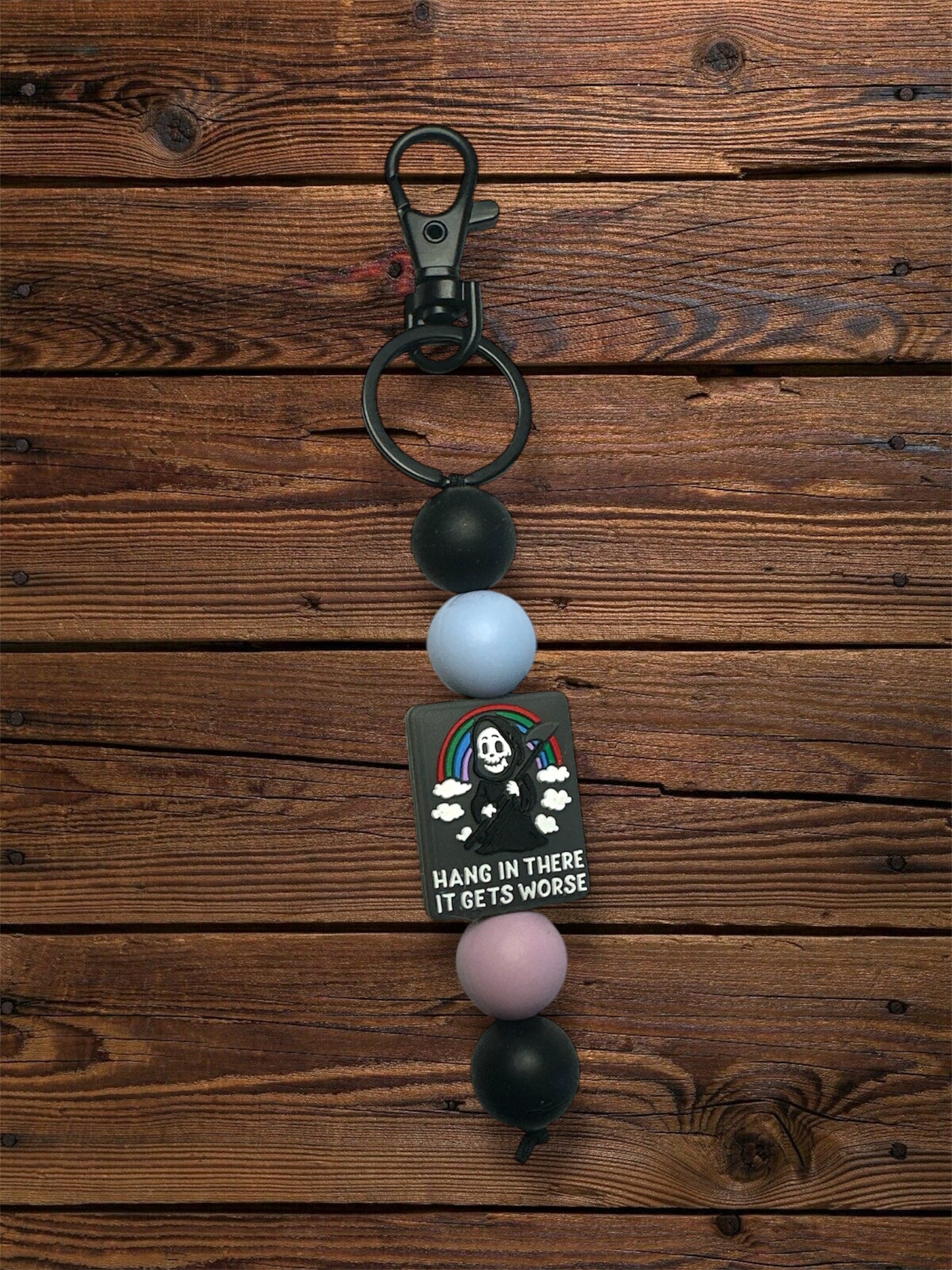 hang in there, it gets worse silicone focal bead, black hardware keychain on a wooden table