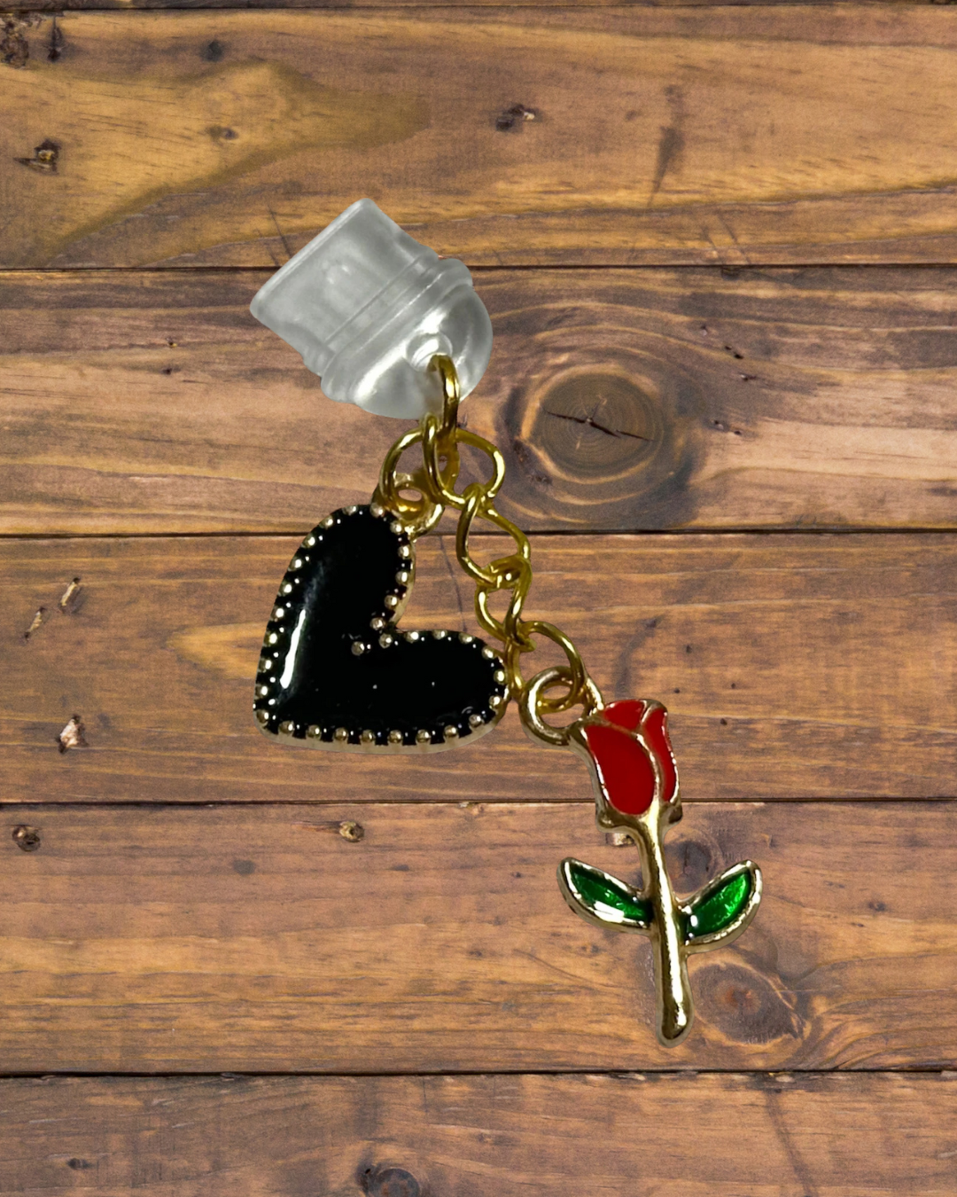 clear dust plug piece with gold chain and a black heart and red rose charm