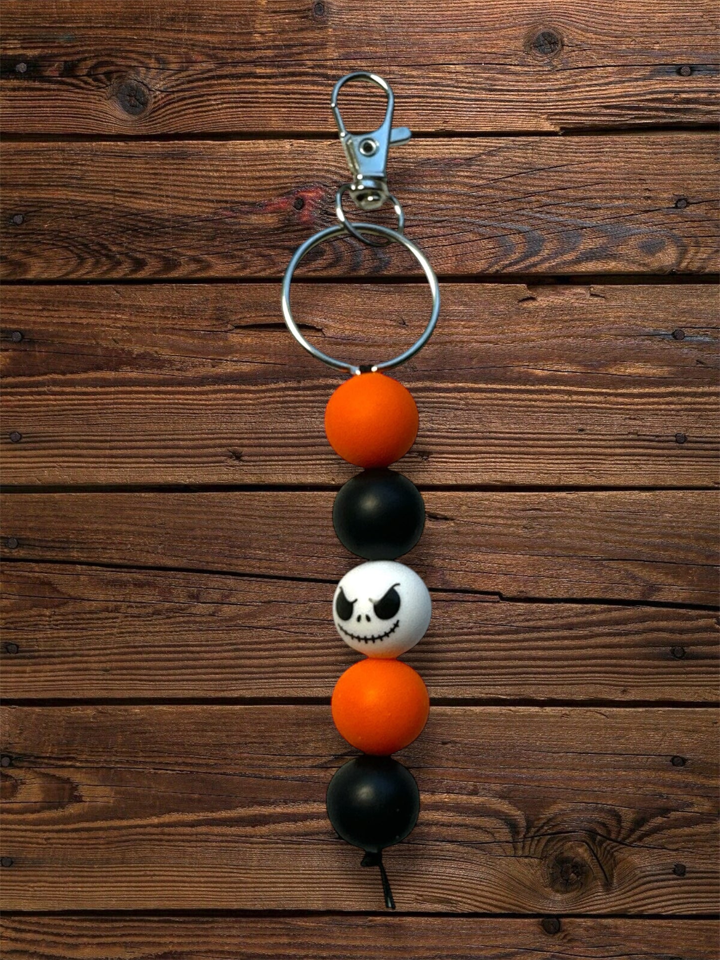orange, black, white, and pumpkin king face silicone beaded keychain with silver keychain hardware