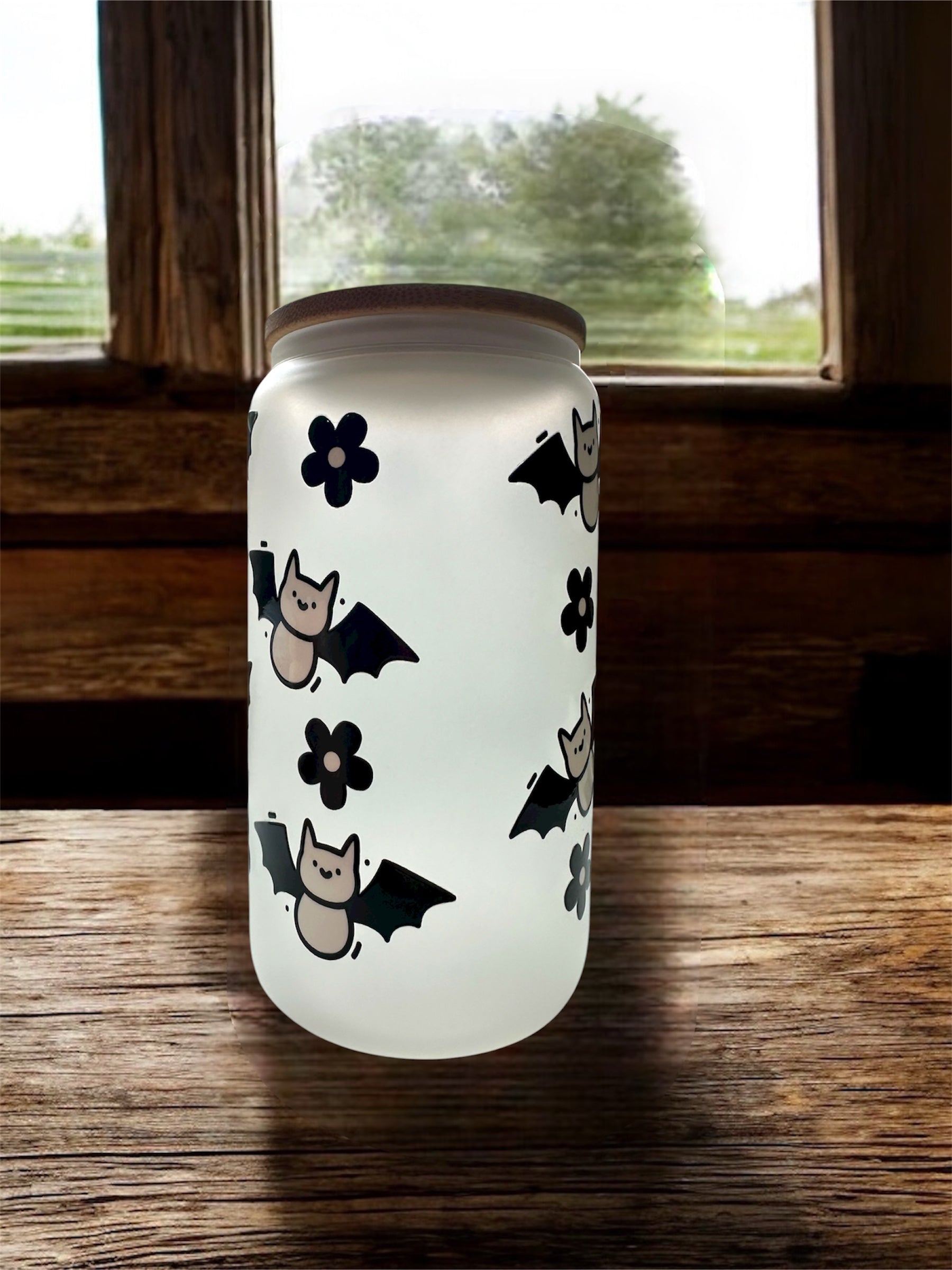 Frosted glass can-shaped tumbler with Halloween-themed design that says 'spooky spooky spooky vibes' on the front, sitting on top of a wooden surface.