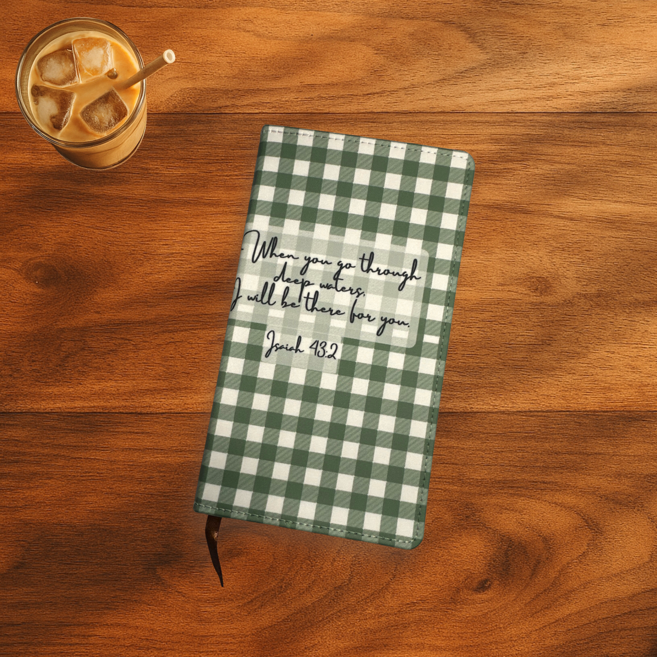 Green and white gingham printed, polyurethane notebook with Isiah 43:2 verse on the front, the notebook is on a wooden surface next to a glass of iced coffee.