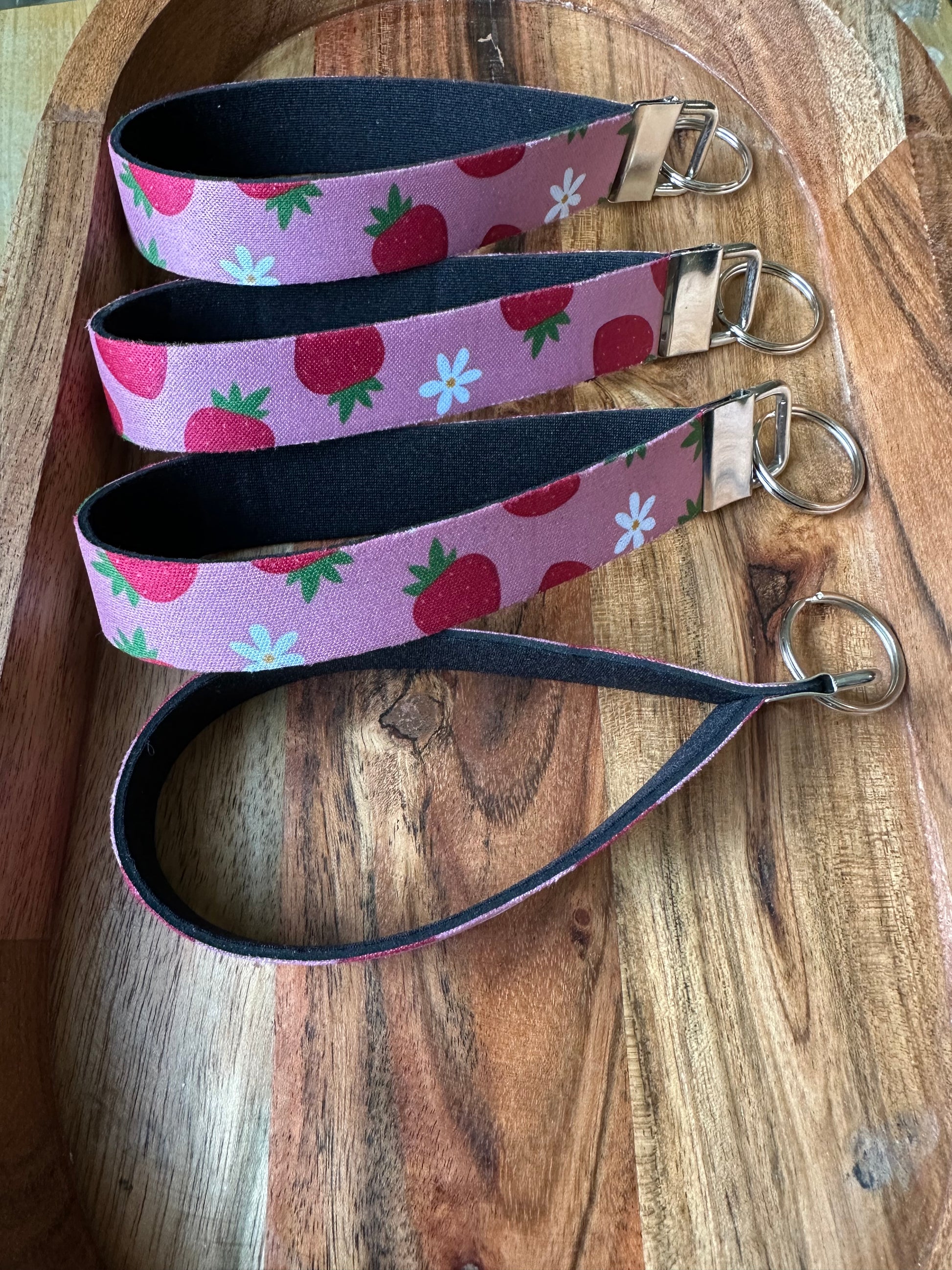 Stack of Neoprene key fobs designed with pink background and strawberries patterned on the front only