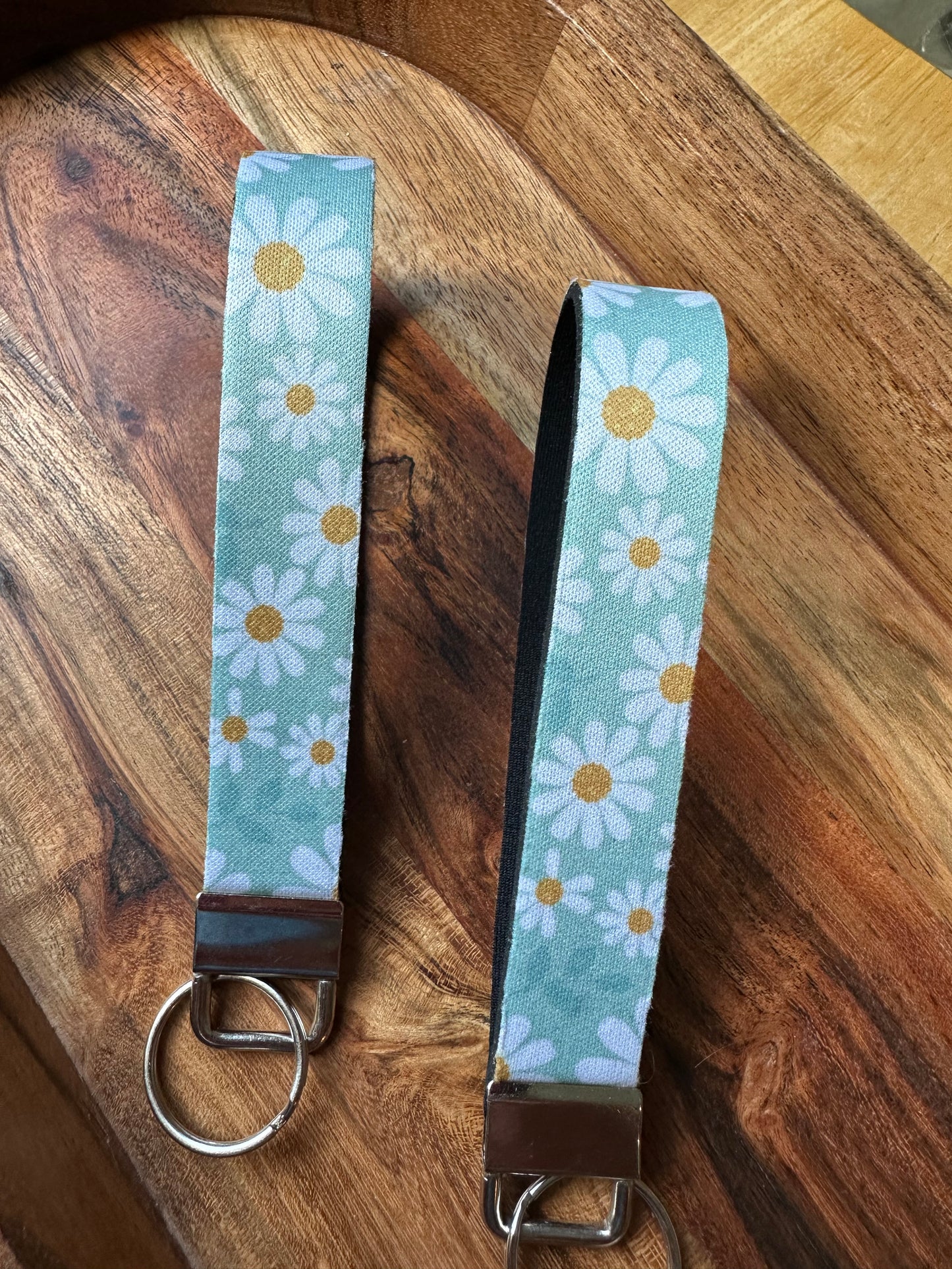 Front picture of neoprene key fob designed with light blue background an daises on the front