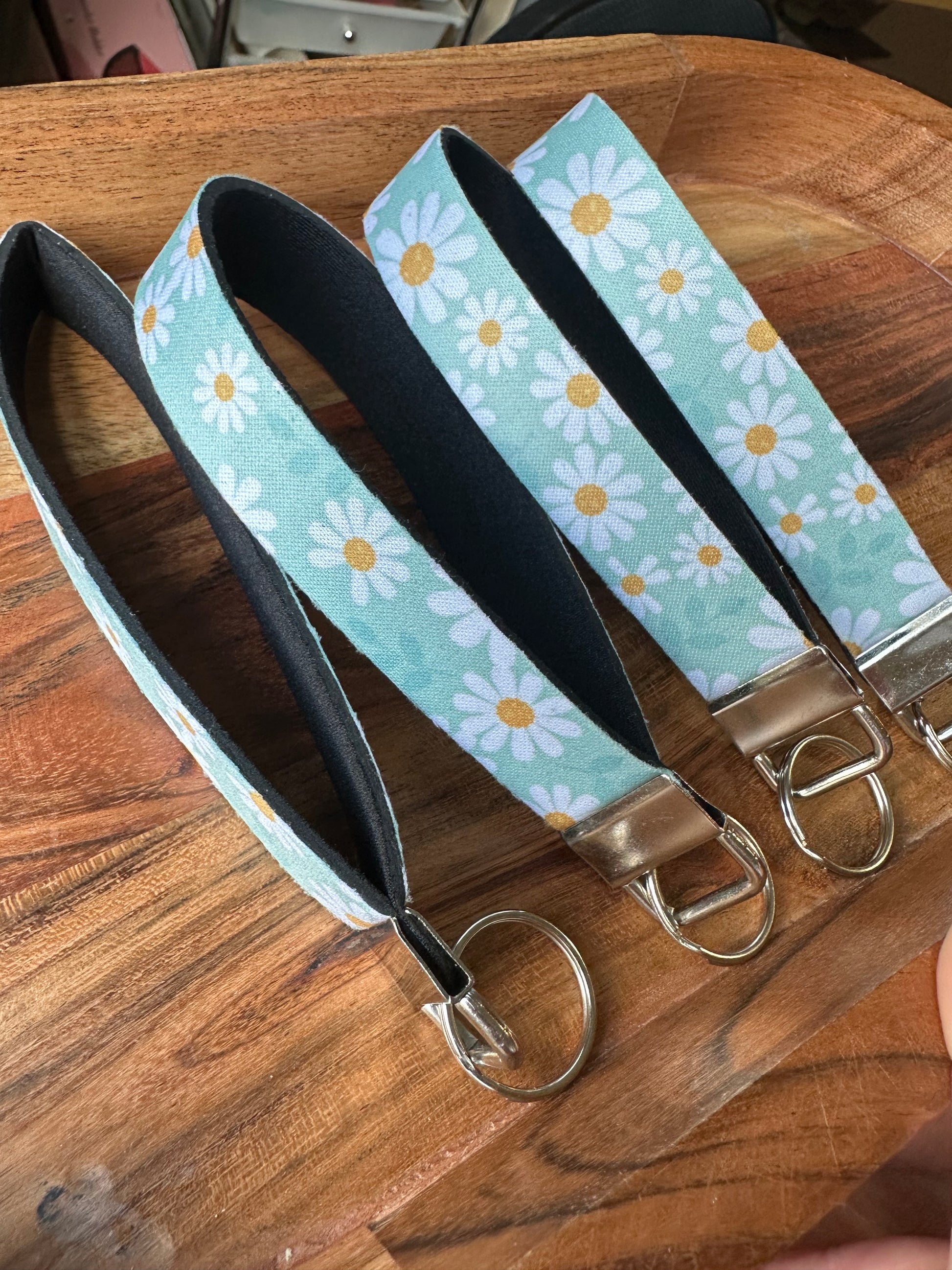 Stack of neoprene key fobs designed with a light blue background and daisies on the front