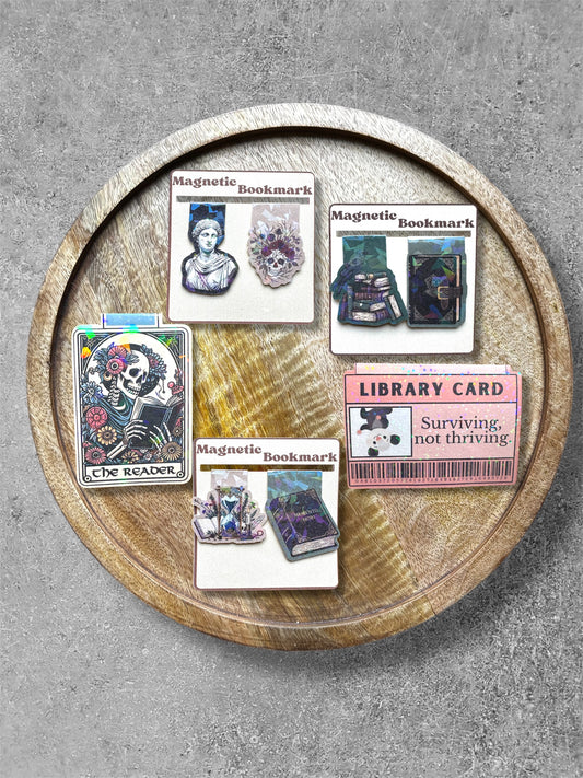 Collection of magnetic bookmarks on a wooden tray with a gray background