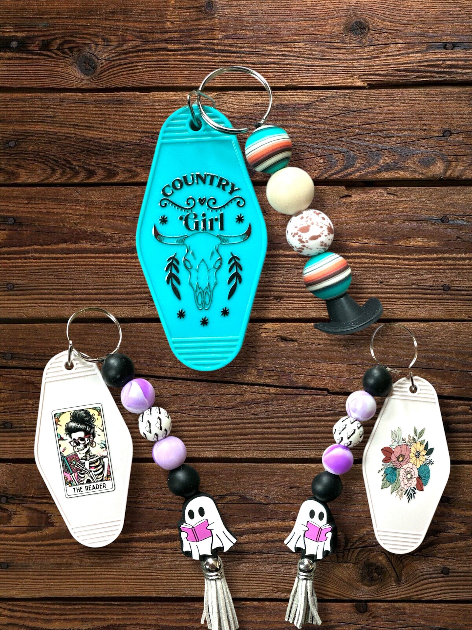 Collection of Motel keychains with silicone beaded keychains on a wooden surface